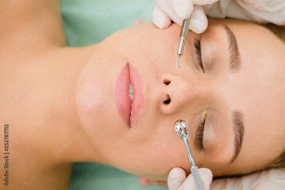 Procedure for cleaning skin with steel tool from blackheads and acne. Deep cleansing of the female face with blackhead remover in the beauty salon. Cosmetologist making receiving cleansing therapy