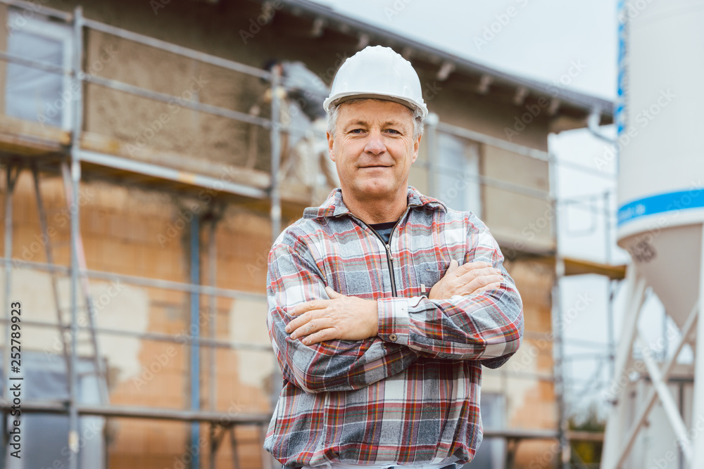 Proud plasterer standing in front of scaffold on construction site Proud plasterer standing in front of scaffold on construction site