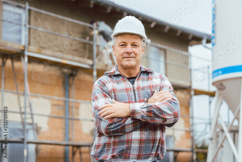 Proud plasterer standing in front of scaffold on construction site