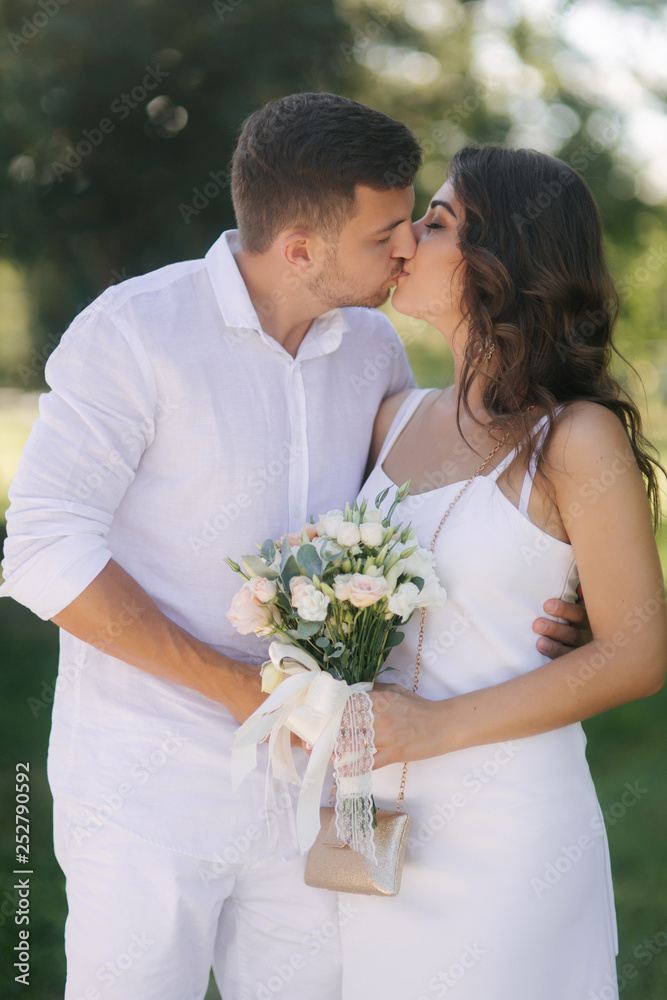 Groom and bride in their wedding day walking in the park. Newlyweds spend time together. Just married
