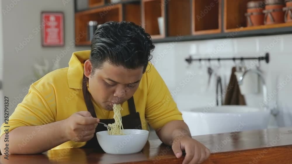Asian man eating instant noodles in the kitchen Asian man eating instant noodles in the kitchen