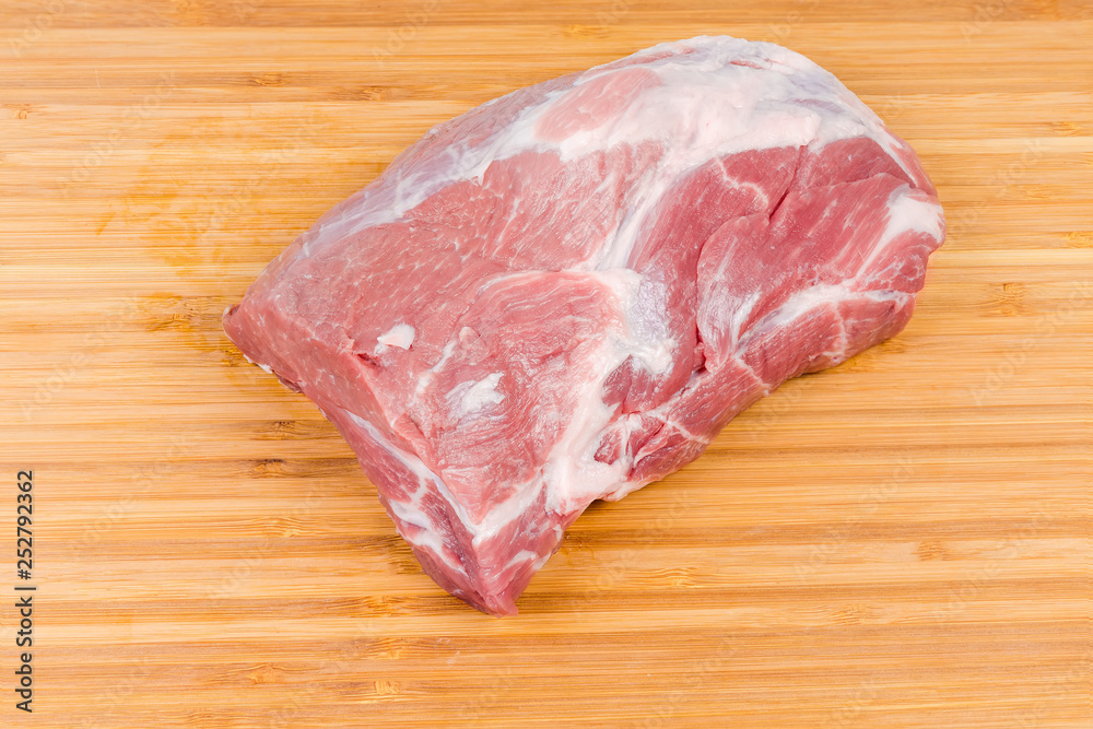 Piece of uncooked pork neck on wooden cutting board Piece of uncooked pork neck on wooden cutting board