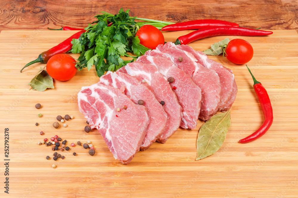 Uncooked steaks of pork neck on the wooden cutting board