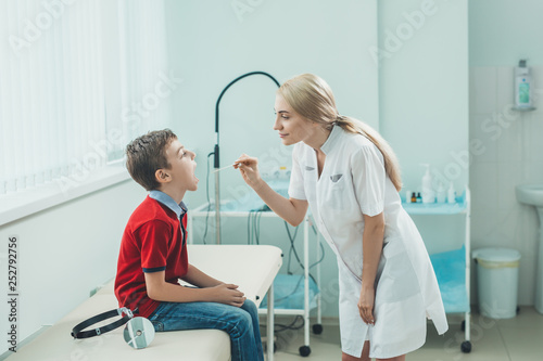 Woman ENT doctor examines  boy s throat. Children s diseases  medical examination.