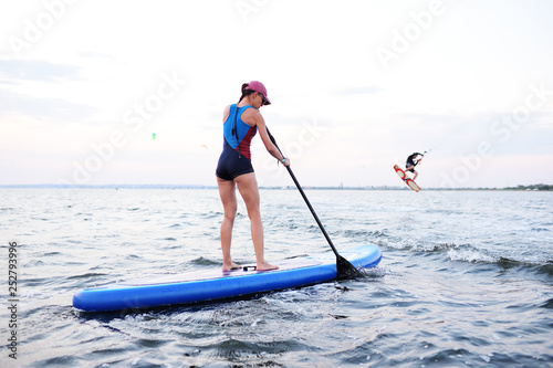 attractive young girl with SUP board on the background of the sea and sunset