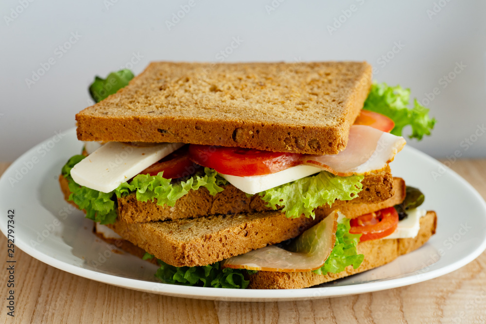 Healthy sandwich with greens, ham, tomatoes and cheese on wooden table Healthy sandwich with greens, ham, tomatoes and cheese on wooden table