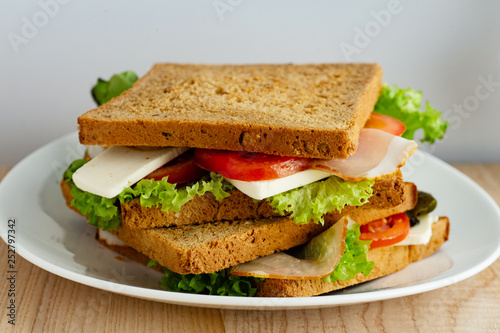 Healthy sandwich with greens, ham, tomatoes and cheese on wooden table