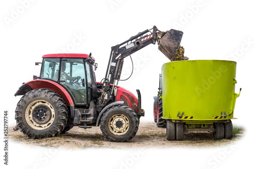 A tractor with a front loader loads silage feed into an animal feed distributor. Isolated photo. Necessary equipment for a dairy farm.