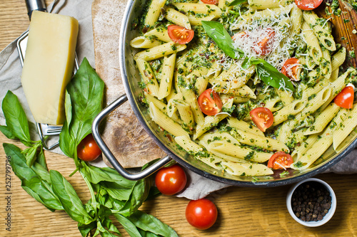 Penne pasta with spinach, cherry tomatoes and Basil. Wooden background, top view