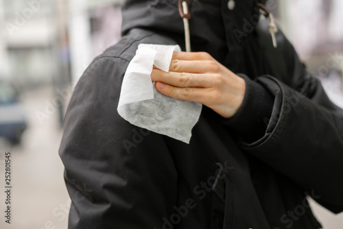 person wipe dirty clothes in the street with paper napkin b