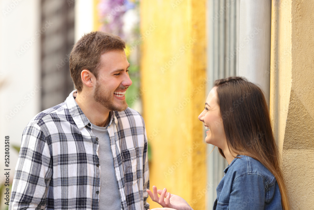 Happy couple talking and laughing in the street Happy couple talking and laughing in the street