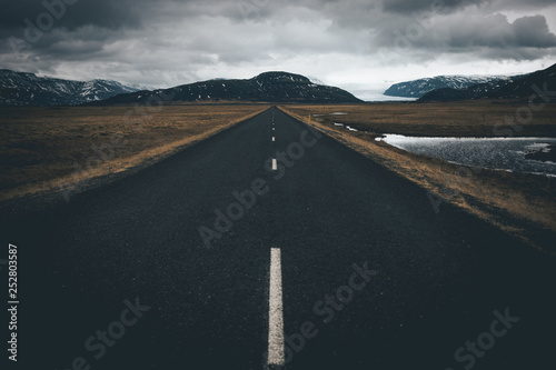 photogenic endless road in iceland leading towards oncoming storm on the horizon 