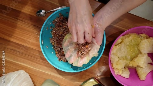 Woman preparing stuffed cabbage rolls with rice and minced meat at home kitchen in slow motion. Very delicious traditional Serbian winter season dish.