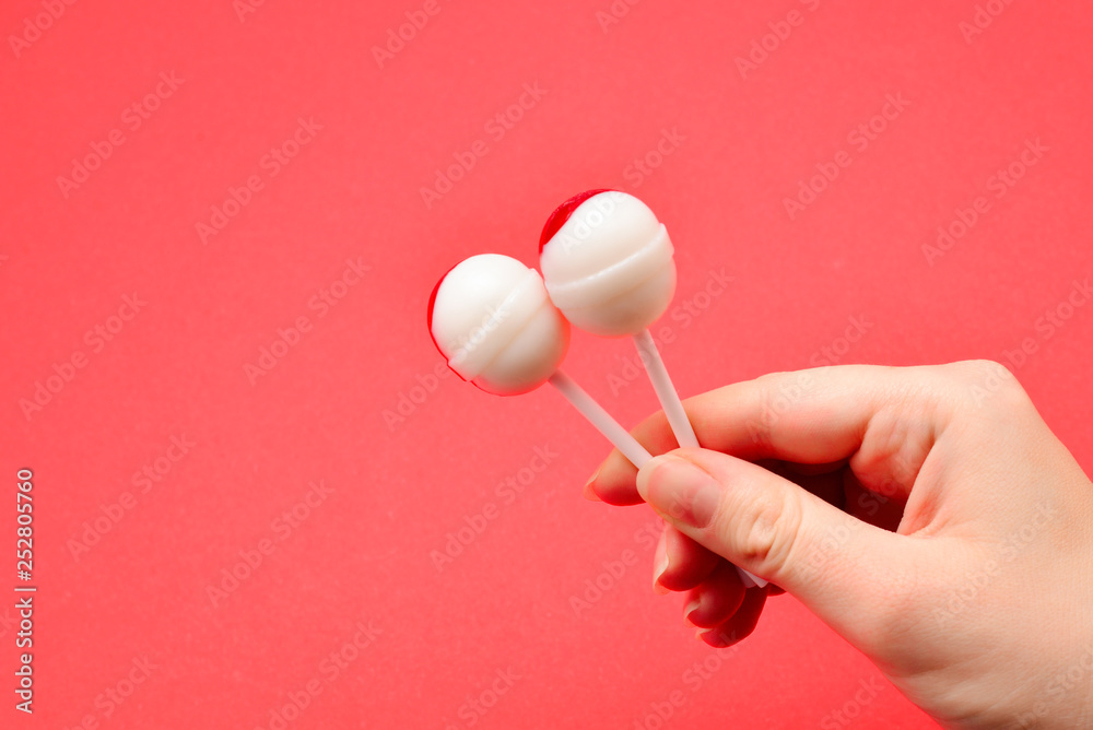 Lollipop in female hand on red background. Space for text or design. Lollipop in female hand on red background. Space for text or design.