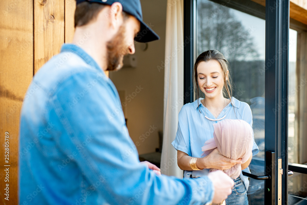 Delivery man bringing some goods packaged in paper bags for a young woman client to home. Buying clothes online and delivery concept Delivery man bringing some goods packaged in paper bags for a young woman client to home. Buying clothes online and delivery concept