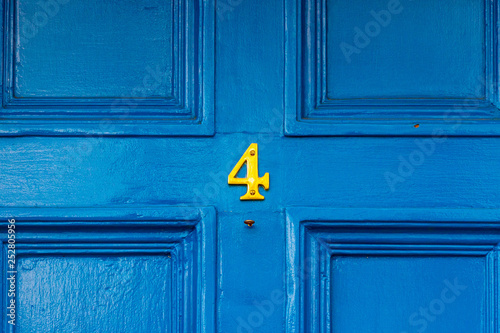House number 4 in bronze on a blue painted wooden door