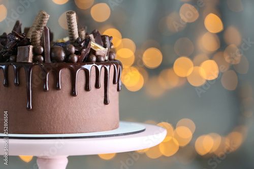 Stand with tasty chocolate cake against defocused lights