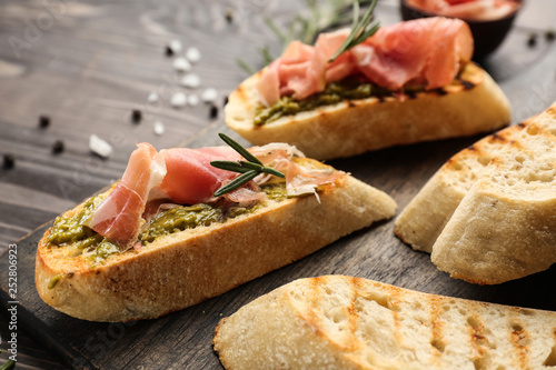 Fresh tasty bruschettas on wooden board, closeup photo