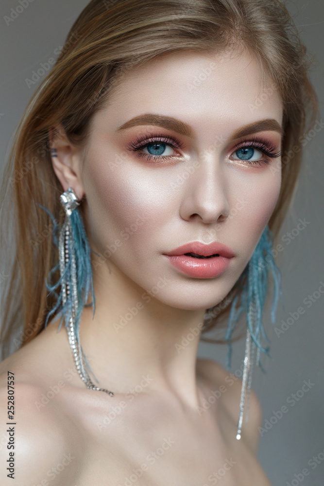 A young girl with long hair, stylish earrings and gentle spring makeup. Beautiful model with shining skin and nude. Portrait made in the studio. wedding look. A young girl with long hair, stylish earrings and gentle spring makeup. Beautiful model with shining skin and nude. Portrait made in the studio. wedding look.