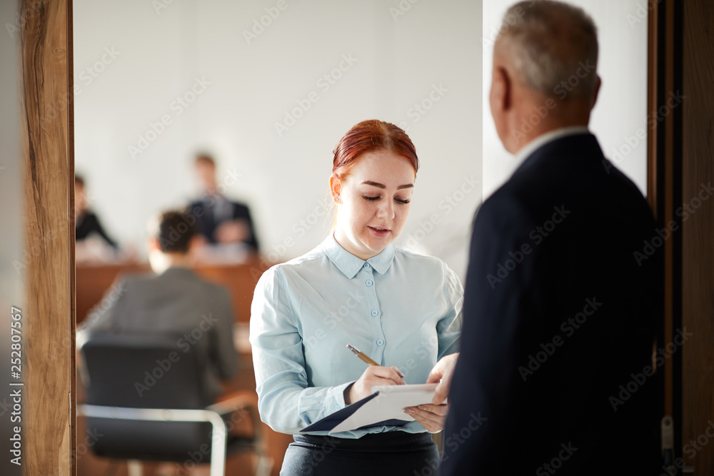 Waist up portrait of young woman holding clipboard talking to boss or business coach, copy space Waist up portrait of young woman holding clipboard talking to boss or business coach, copy space