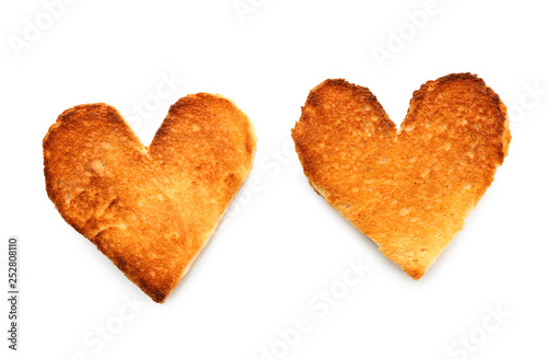 Heart-shaped slices of toasted bread on white background