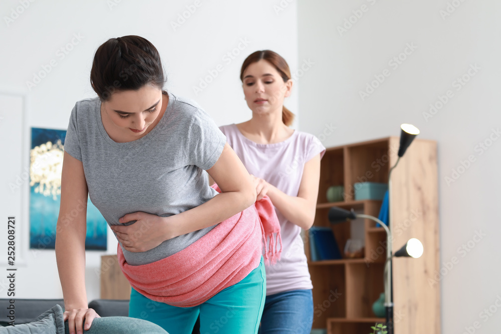 Doula massaging pregnant woman at home