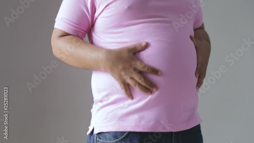 portrait of young fat man pinch his belly