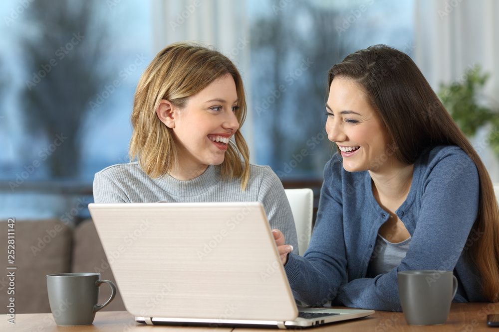 Happy friends using laptop and talking at home Happy friends using laptop and talking at home
