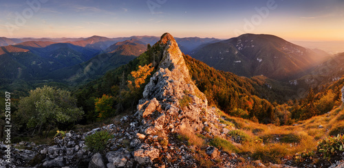 Mountain autumn panorama at sunset with forest and rocks.