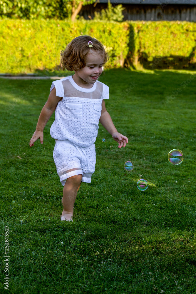 Beautiful little girl playing with soap bubbles summer park. Portrait closeup. Beautiful little girl playing with soap bubbles summer park. Portrait closeup.