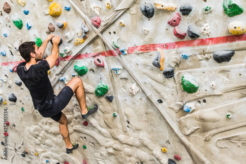 Man practicing rock climbing on artificial wall indoors. Active lifestyle and bouldering concept..