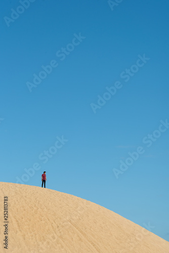 alone young male asian standing on top of sand dune. concept of success and travel