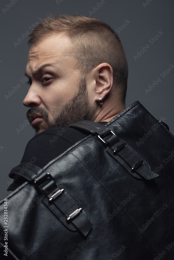 Forever Black concept. Attractive handsome man in trendy casual clothing with leather bag over gray background. Close up. Studio shot Forever Black concept. Attractive handsome man in trendy casual clothing with leather bag over gray background. Close up. Studio shot