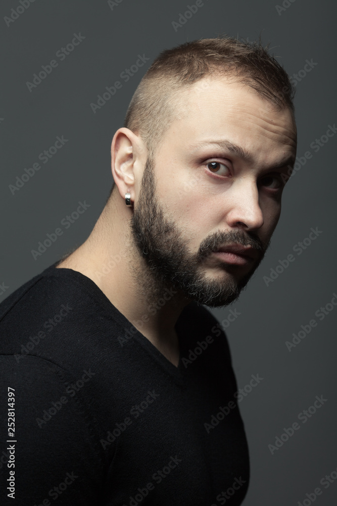 Fototapeta premium Male beauty concept. Fabulous at any age. Portrait of 35-year-old man standing over dark gray background. Modern haircut. Rocker, biker style. Close up. Studio shot