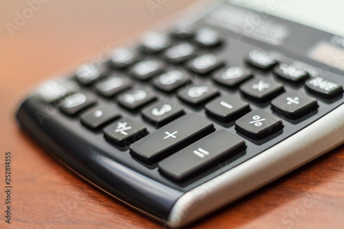 Math calculator number pad keys isolated on a dark wood table with blurred background