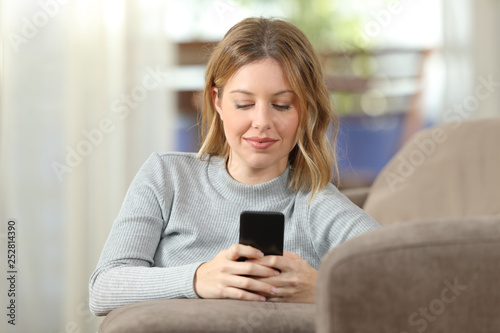 Serious lady texting on phone at home