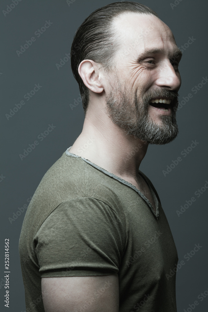 Male beauty concept. Fabulous at any age. Portrait of 40-year-old man  laughing over dark gray background. Hair brushed back. Rocker, biker style.  Close up. Studio shot Stock Photo | Adobe Stock