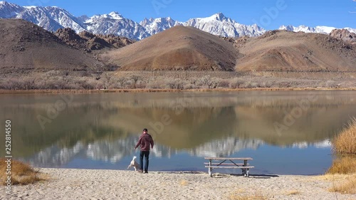 A man and his dog enjoy a beautiful day at a lake at the base of Mt. Whitney and the Sierra Nevada mountains near Lone Pine, California.