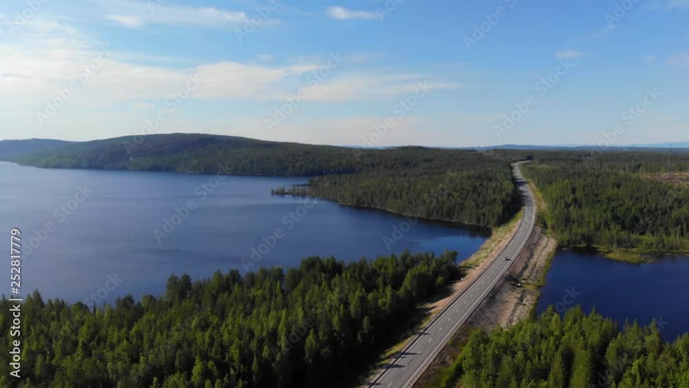 Flying over the road, which is located between two lakes. Passenger car overtakes the truck. Beautiful forest naturalness. Flying over the road, which is located between two lakes. Passenger car overtakes the truck. Beautiful forest naturalness.