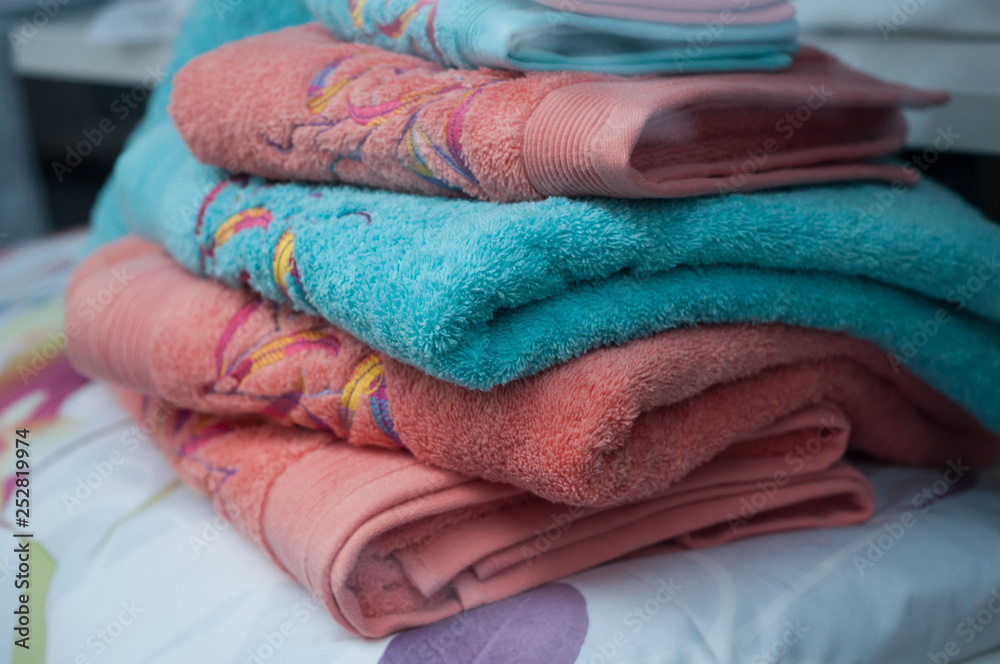 closeup of colorful bath towels pile on bed in decoration store showroom closeup of colorful bath towels pile on bed in decoration store showroom