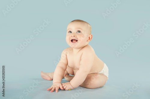 naked baby crawls on an isolated blue background and plays with the phone. The concept of education and health