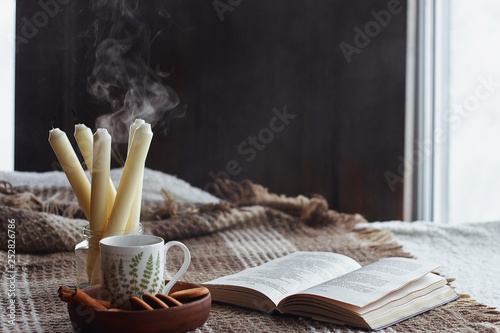 Home interior of living room. Woolen blanket and a cup of tea with steam. Breakfast on the couch in the morning sun. Cozy autumn or winter concept. Hyugge comfort photo