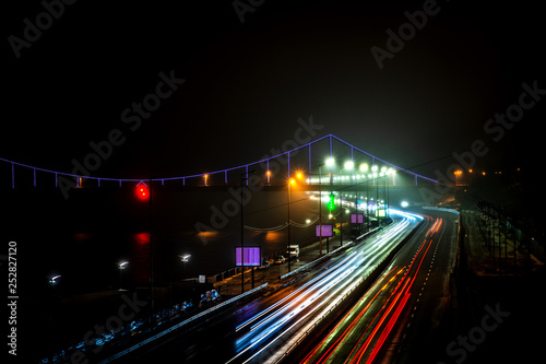 Glowing footbridge in the night fog and headlights of cars. Kyiv. Ukraine
