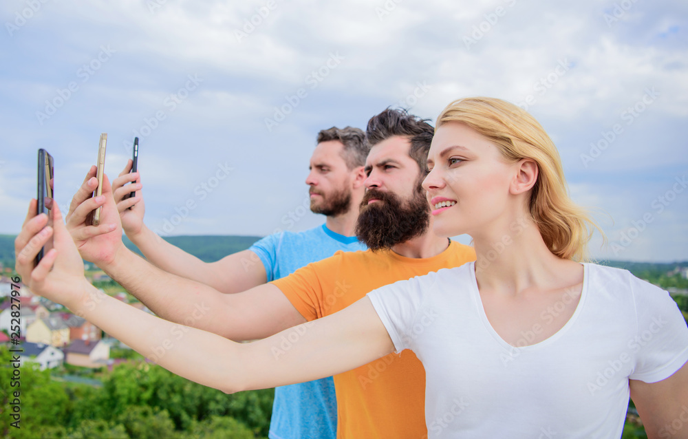 Experiencing digital picture sharing. Best friends taking selfie with camera phone. People shooting selfie on nature. Sexy woman and men holding smartphones in hands. Sharing selfie on social network Experiencing digital picture sharing. Best friends taking selfie with camera phone. People shooting selfie on nature. Sexy woman and men holding smartphones in hands. Sharing selfie on social network