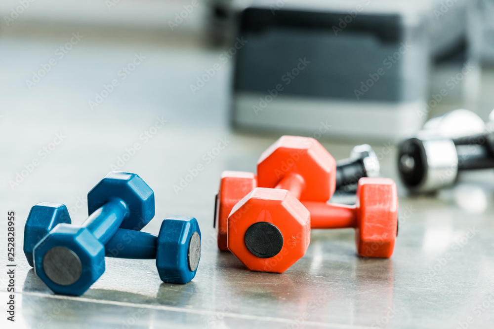 selective focus of metallic multicolored fitness dumbbells in gym