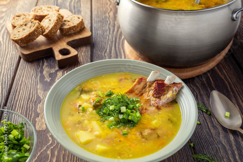 Fragrant yellow split pea soup with smoked pork ribs on a wooden table.