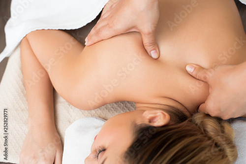 Body Massage on specific naked back of Mix Race Caucasian Asian woman by pressing fingers on pain or stress muscle point to release relax. Therapist Spa body massage woman hands treatment on customer