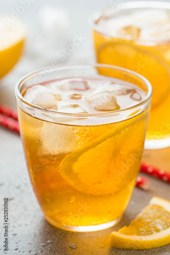 Cold tea with lemon and ice in a glass with drops, fresh sweet fruit drink, summer freshness, delicious lemonade