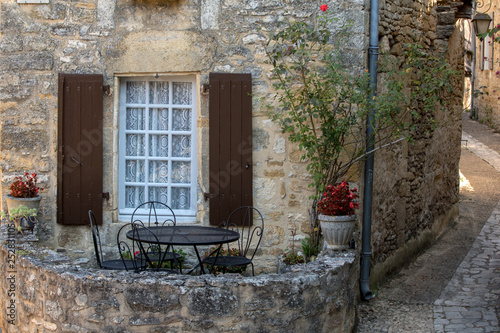 A black metal table and chairs on the romantic terrace of an old stone house in Beynac-et-Cazenac, France