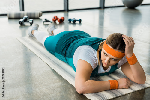 Fototapeta Naklejka Na Ścianę i Meble -  exhausted overweight girl lying on fitness mat in gym